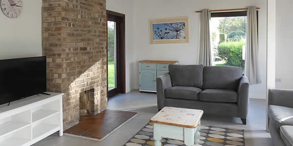 Light and spacious lounge with comfortable sofas and TV in one of our standard cottages
